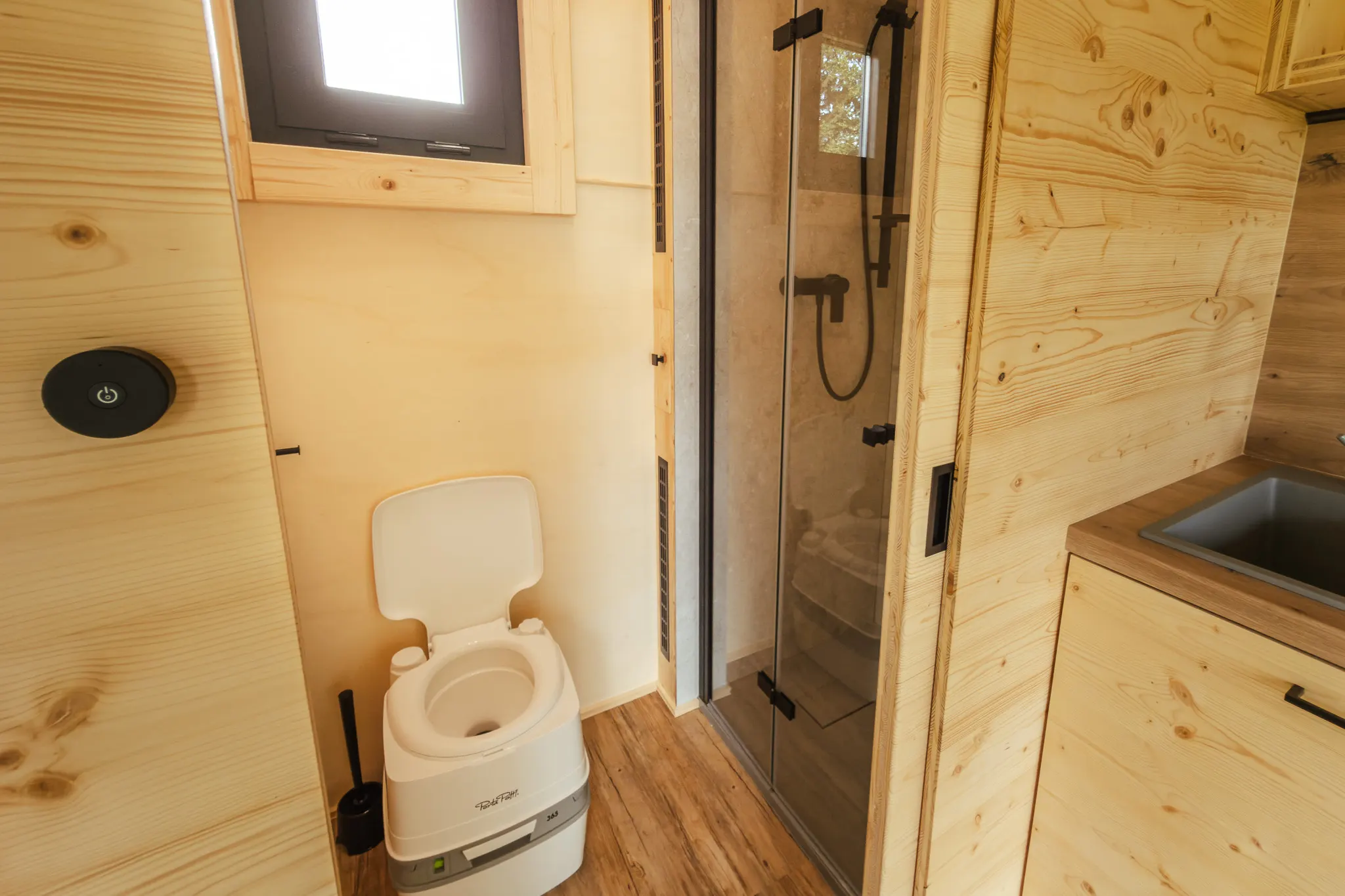 Prosklený sprchový kout a chemické WC v jedné místnosti